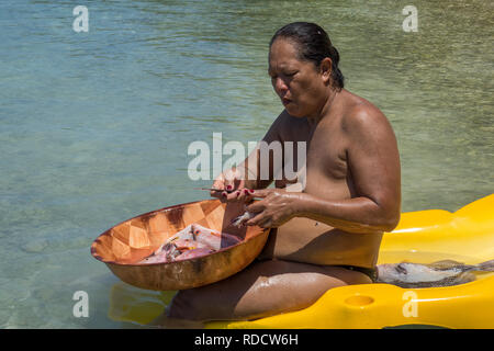 Polinesia francese, Rangiroa Atoll, lady sulla spiaggia eviscerazione pesce Foto Stock