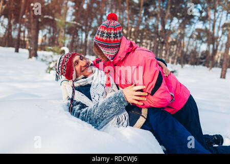 Coppia senior abbracciando nella foresta d'inverno. L uomo e la donna che giace nella neve e divertimento nel giorno di San Valentino in esterno Foto Stock