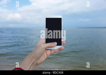 Mani femminili con smart phone a scattare foto di mare spazio copia Foto Stock