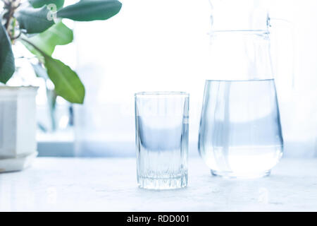 Bicchiere di vetro e la brocca di acqua fredda su un vassoio Bicchiere di vetro e la caraffa con acqua su un tavolo