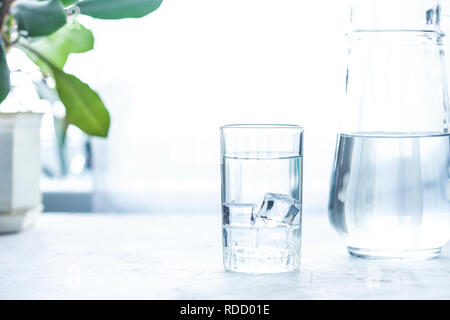 Bicchiere di vetro e una caraffa di acqua, ghiaccio, menta e Bicchiere di vetro e la caraffa con acqua su un tavolo