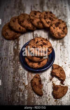 Gruppo di gustosi biscotti accanto a una ciotola su una vecchia tavola di legno Foto Stock