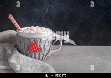 Cioccolata calda con marshmallows, cuore rosso sulla tazza sul tavolo. Il giorno di San Valentino sfondo con lo spazio di testo Foto Stock