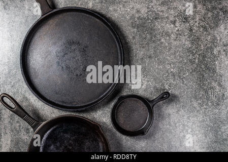 Diversi Ghisa padelle o Skillets per una sana cottura su sfondo grigio Foto Stock