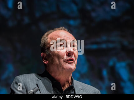 18 gennaio 2019, Renania-Palatinato, Mainz: Robert Menasse, scrittore austriaco e vincitore del 2019 Carl Zuckmayer medaglia, darà un discorso di ringraziamento presso lo Staatstheater. Sullo sfondo è possibile vedere un dettaglio proiezione del busto Carl-Zuckmayer in piedi in Nackenheim. La medaglia è donato in memoria dello scrittore e drammaturgo che era nato a Nackenheim. Il premio riconosce i meriti per la lingua tedesca ed è presentato annualmente. Foto: Andreas Arnold/dpa Foto Stock