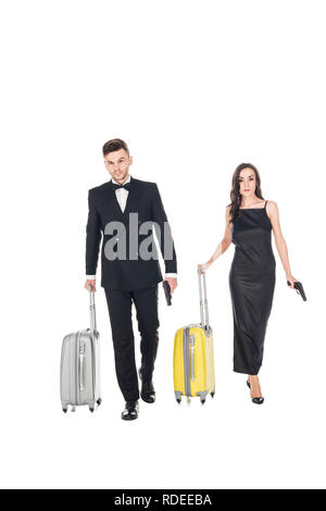 Elegante coppia di agenti segreti vestiti di nero con le pistole e borse da viaggio, isolato su bianco Foto Stock