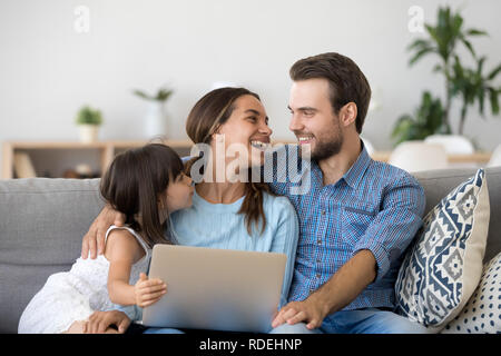 La famiglia felice di tre bonding utilizzando laptop seduto sul lettino Foto Stock