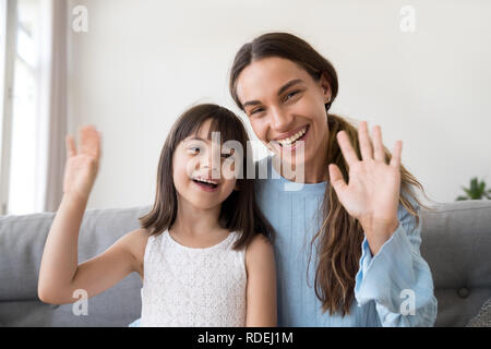 Felice mamma e figlia di capretto sventolare le mani guardando la fotocamera Foto Stock