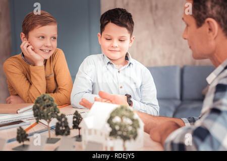 Due smart curioso ragazzi ascolto attento al loro zio Foto Stock