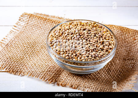 Materie le lenticchie in una ciotola di vetro sulla pietra nera dello sfondo. Una sana alimentazione vegetariana concetto. Superfoods. Copia dello spazio. Le lenticchie sono ricche di carbohydra complesse Foto Stock