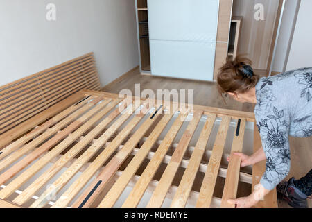 Donna anziana che assembla il suo nuovissimo letto in legno organico in una camera da letto appena arredata come nuovo concetto di casa Foto Stock