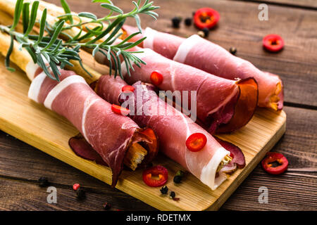 Fette di pane con prosciutto o grissini stick con il prosciutto italiano tradizionale di antipasti, piatti Foto Stock