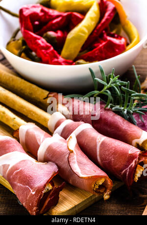 Fette di pane con prosciutto o grissini stick con il prosciutto italiano tradizionale di antipasti, piatti Foto Stock