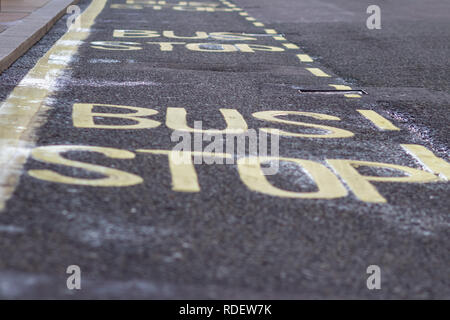 Segnali stradali fermata bus giallo parola scritta su asfalto Foto Stock