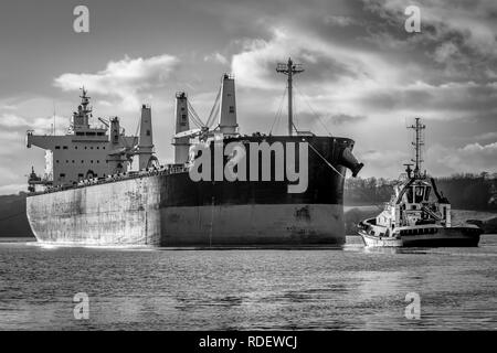 Una foto di una nave cargo che entrano in porto trainato da un rimorchiatore Foto Stock