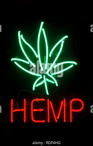 Insegna al neon pubblicità la canapa con una stilizzata foglia di marijuana incandescente contro uno sfondo nero Foto Stock