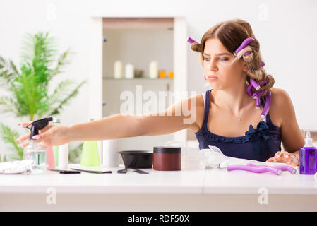 Giovane donna con arricciacapelli in Barberia Foto Stock