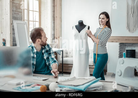 Dai capelli scuri permanente designer vicino a forma del vestito di bianco abiti lunghi Foto Stock
