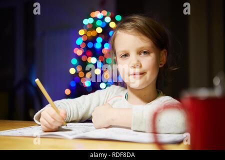 Ispirato bambina al tavolo a disegnare con matite colorate o fare lavoro a casa Foto Stock