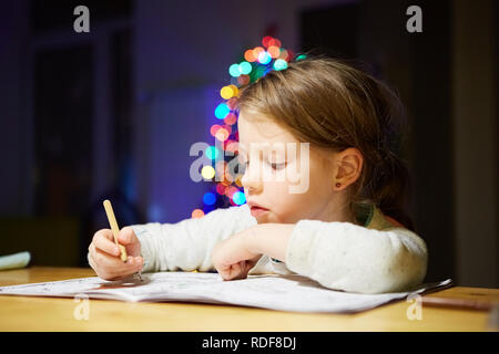 Ispirato bambina al tavolo a disegnare con matite colorate o fare lavoro a casa Foto Stock