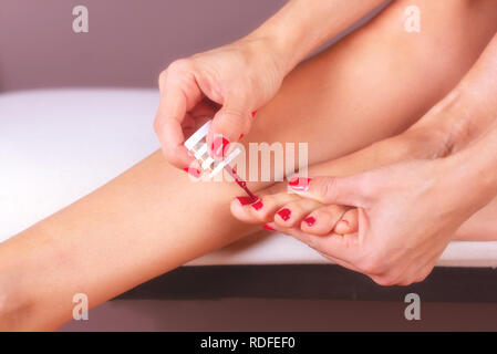 Donna facendo cura dei piedi e delle unghie di trattamento. Applicazione di rosso smalto per unghie . Foto Stock