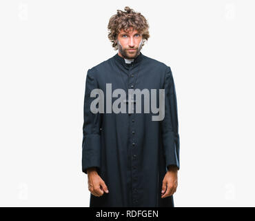 Bello ispanica sacerdote cattolico uomo sullo sfondo isolato premuto e la preoccupazione per la sofferenza, gridando arrabbiato e paura. Triste espressione. Foto Stock