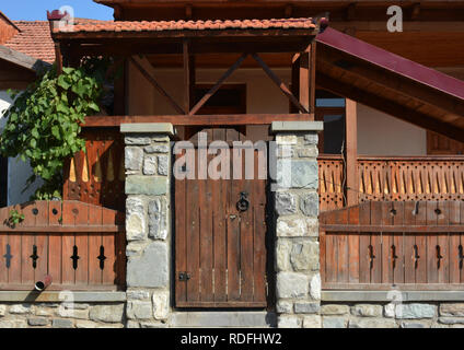 Vecchia casa con porta in legno e piante verdi sul villaggio. Vecchie porte in legno con anello. Foto Stock