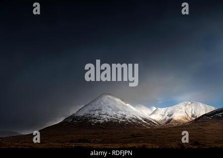 Moor paesaggio con cime innevate dei monti Cullins di fronte drammatico nuvole nel paesaggio delle highland, Sligachan Foto Stock