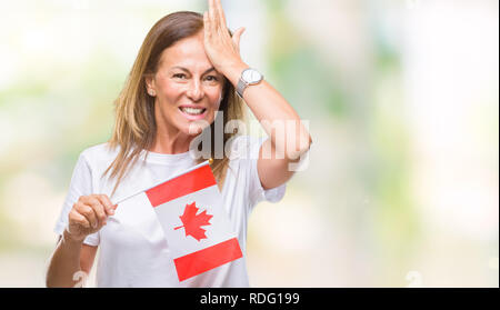 Medioevo donna ispanica holding bandiera del Canada su sfondo isolato ha sottolineato con la mano sulla testa, sconvolto con vergogna e la sorpresa di fronte, e arrabbiato Foto Stock