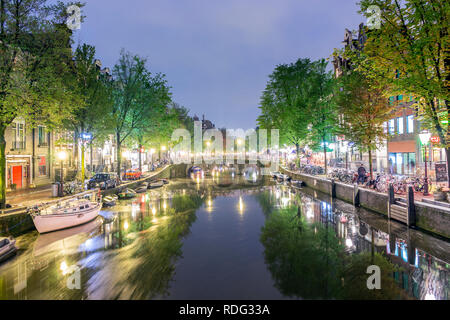 Bel canale con barche e biciclette su strada di notte a Amsterdam, Olanda Foto Stock