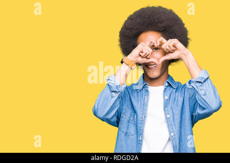 Giovane americano africano uomo con capelli afro facendo forma di cuore con la mano e le dita sorridente guardando attraverso il segno Foto Stock