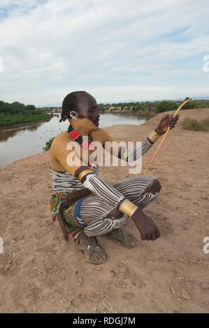 Karo uomo con del corpo e del viso dipinti seduto sul suo appoggiatesta, Omo river valley, l'Etiopia meridionale, Africa Foto Stock