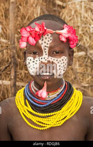 Karo ragazza con un archetto floreali, pitture facciali e colorati di collane e labbro piercing, Omo river valley, sud Etiopia Foto Stock