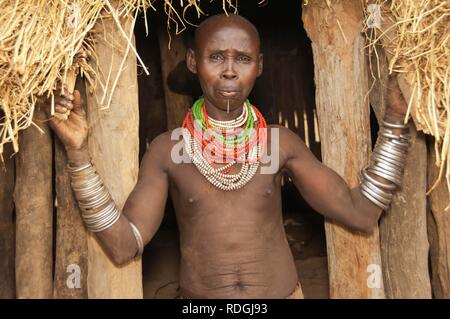 Karo donna con un sacco di colorati collane e cowry conchiglie, labbro piercing e dipinti del viso nella parte anteriore del suo rifugio Foto Stock