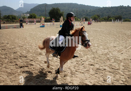 Giovani piloti competere sui loro cavalli e poney su un locale competizione equestre nell'isola spagnola di Ma Foto Stock