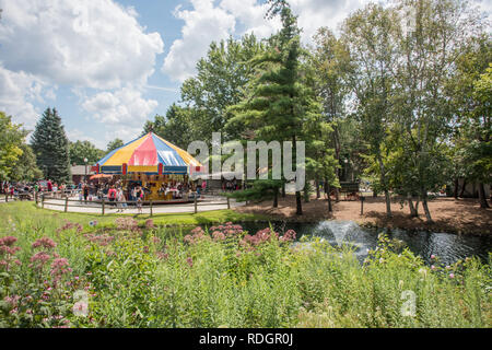 Aurora, Illinois, Regno States-August 9, 2017: vegetazione lussureggiante, fontana e le persone che si godono la giostra ride a Blackberry Farm in Aurora, Illinois Foto Stock