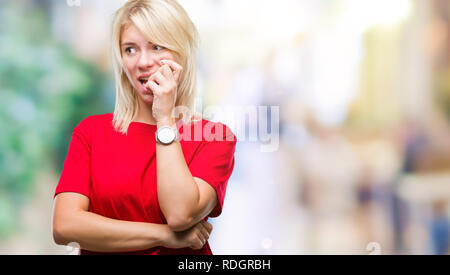 Giovane bella donna bionda che indossa t-shirt rossa su sfondo isolato cercando stressato e nervoso con le mani sulla bocca di mordere le unghie. Ansia probl Foto Stock