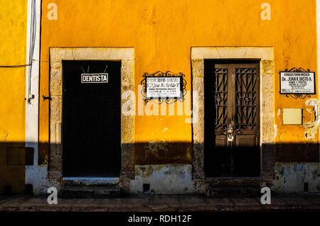 Strade giallo facciate di Izamal, chiamato 'giallo città', con porte coloniale di negozi al dettaglio e le imprese, in Yucatan, Messico Foto Stock