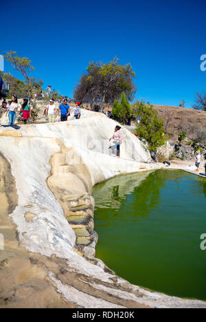 I turisti da un lago fatto da cascate pietrificate, Hierve el Agua, Oaxaca, Messico Foto Stock