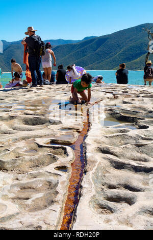 I turisti da un lago fatto da cascate pietrificate, Hierve el Agua, Oaxaca, Messico Foto Stock