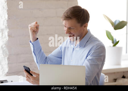 Imprenditore entusiasta celebra il raggiungimento di business utilizzando il phon Foto Stock