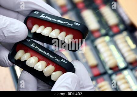 Laboratorio Odontotecnico, fabbricazione di protesi dentarie da parte di un maestro artigiano, confrontando il colore del dente sulla base di campioni di colore Foto Stock