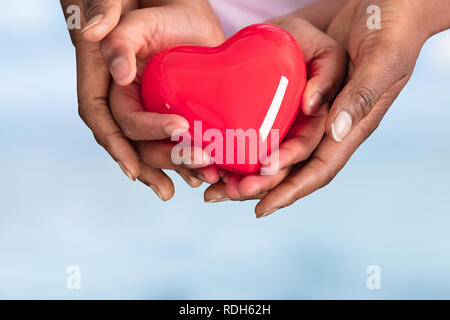 La madre e il Bambino Mani cuore rosso su sfondo blu Foto Stock