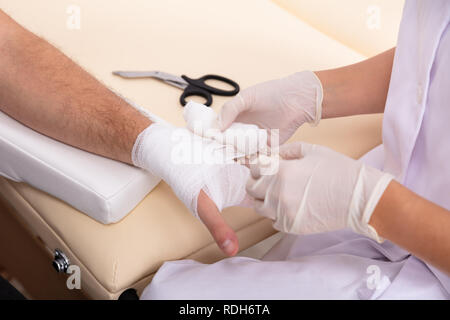 Close-up di medico bendaggio di legatura sul maschio di mano del paziente Foto Stock