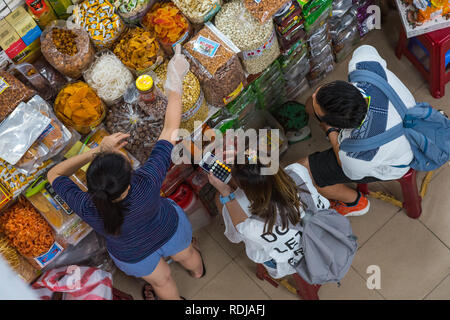 Danang, Vietnam - 14 Ottobre 2018: una giovane donna traveler, accompagnato da un uomo, conteggi spese su calcolatrice in Cho mercato Han. Foto Stock