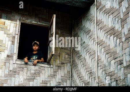 Luang Namta / Laos - Lug 06 2011: boy guardando fuori di un tipico asiatico murata di bambù Foto Stock