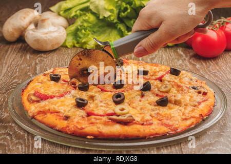 Pizza di taglio a fette con coltello speciale Foto Stock