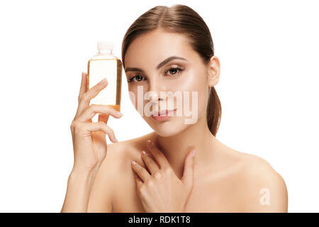 Concetto di bellezza. La Caucasian pretty woman con una pelle perfetta tenendo la bottiglia di olio in studio. La bellezza, la cura della pelle, trattamento, salute, spa, di cosmetici e di concetto di pubblicità Foto Stock