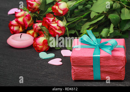 Il giorno di San Valentino concetto.rose rosse e confezione regalo su uno sfondo di legno (fuoco selettivo). Foto Stock