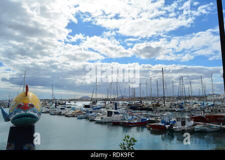 Un pesci colorati figura sul dock di Corralejo. Corralejo pier e brillante Oceano in background. Scenic sky. Fuerteventura, Spagna. Foto Stock
